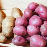 Close-up of fresh red and brown potatoes stored in a wooden crate.
